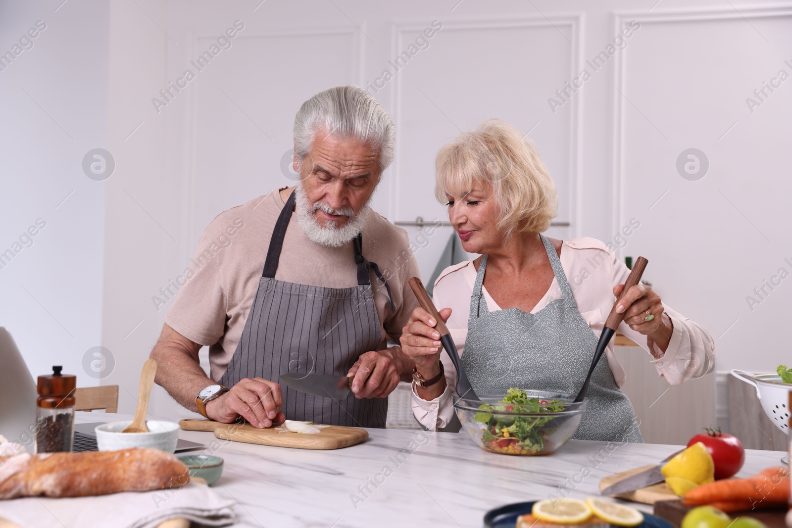 Elderly couple cooking together at marble table in kitchen Photo of Elderly couple cooking together at marble table in kitchen