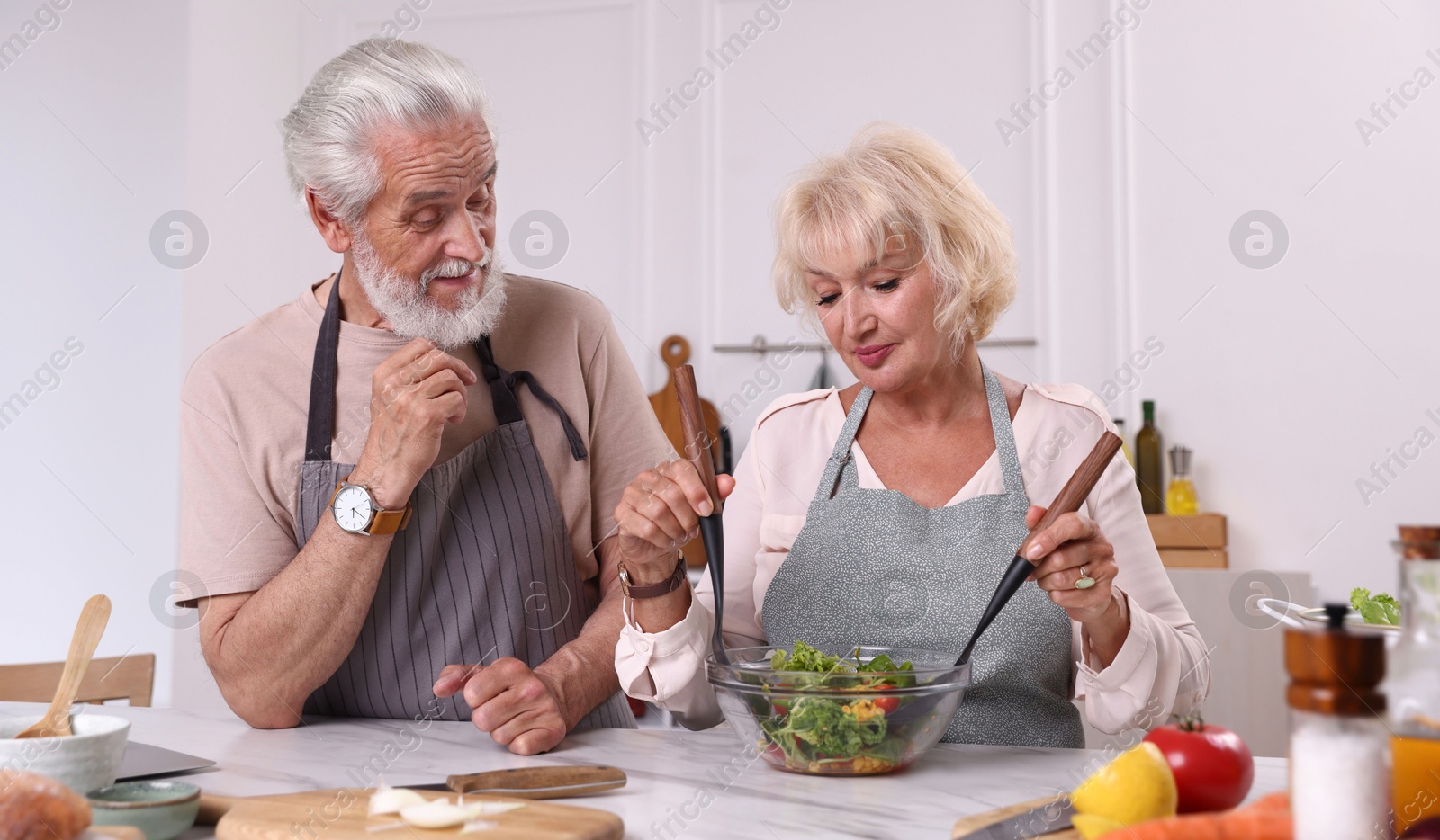 Elderly couple cooking together at marble table in kitchen Photo of Elderly couple cooking together at marble table in kitchen