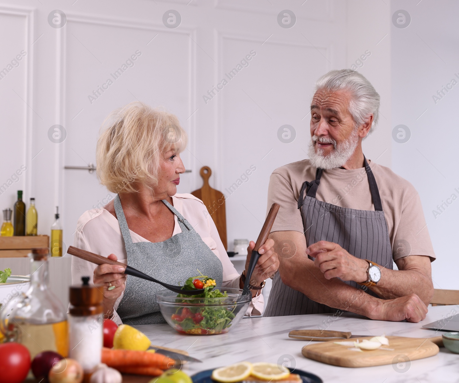 Elderly couple cooking together at marble table in kitchen Photo of Elderly couple cooking together at marble table in kitchen