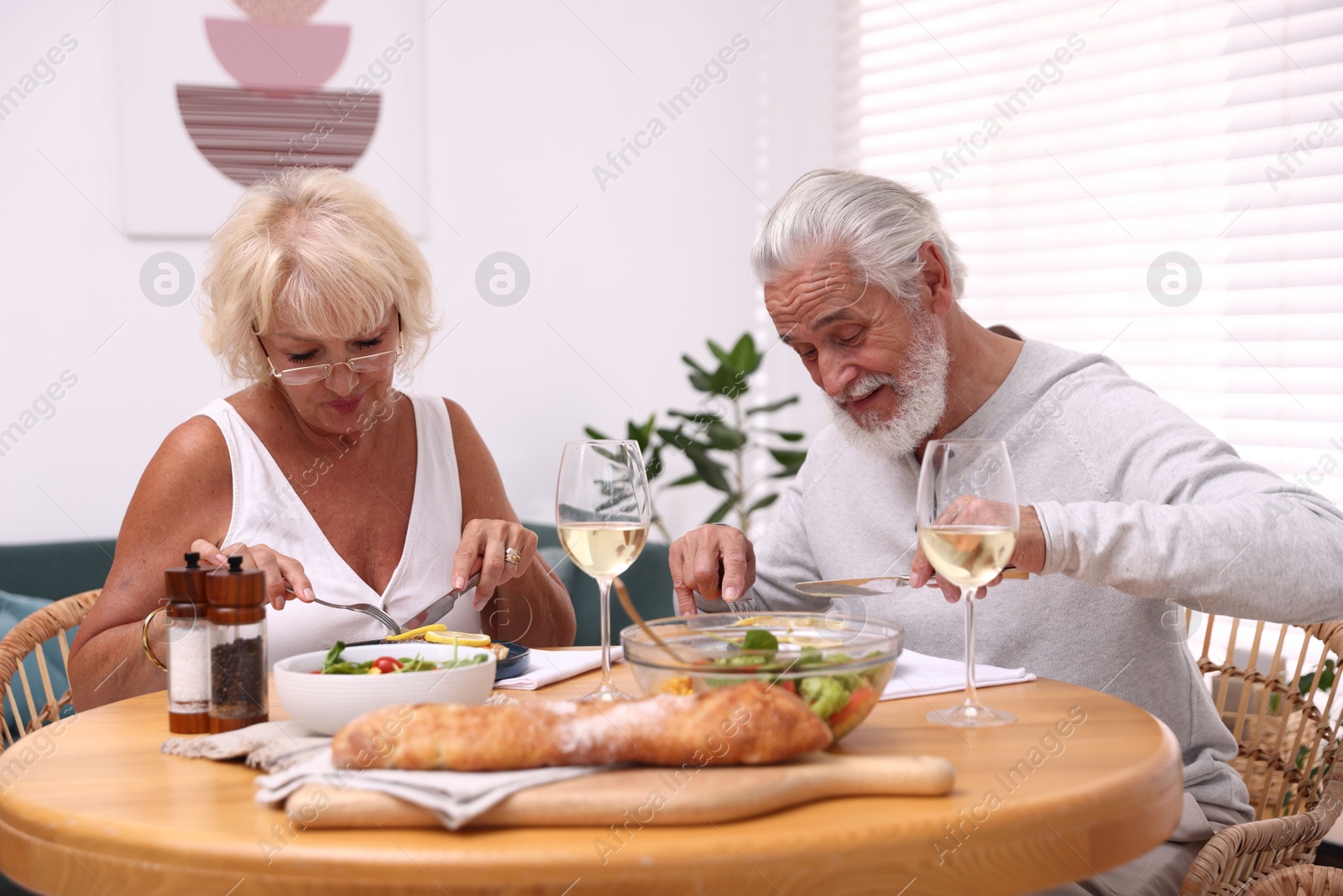 Elderly couple having dinner at table indoors Photo of Elderly couple having dinner at table indoors