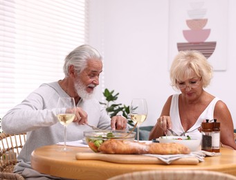 Photo of Elderly couple having dinner at table indoors