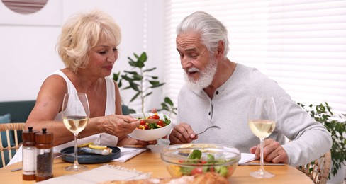 Photo of Elderly couple having dinner at table indoors