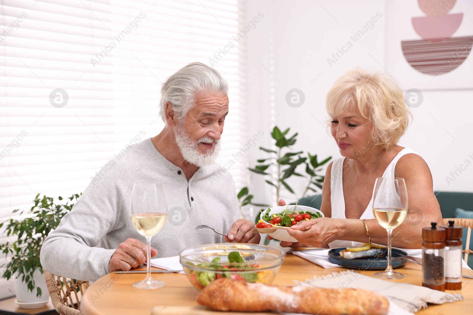 Elderly couple having dinner at table indoors Photo of Elderly couple having dinner at table indoors