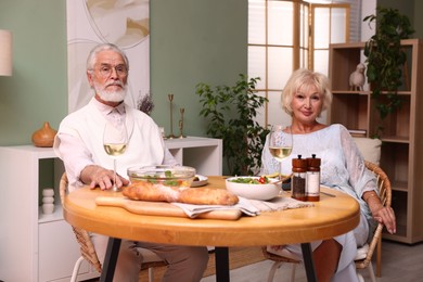 Photo of Portrait of elderly couple having dinner at table indoors