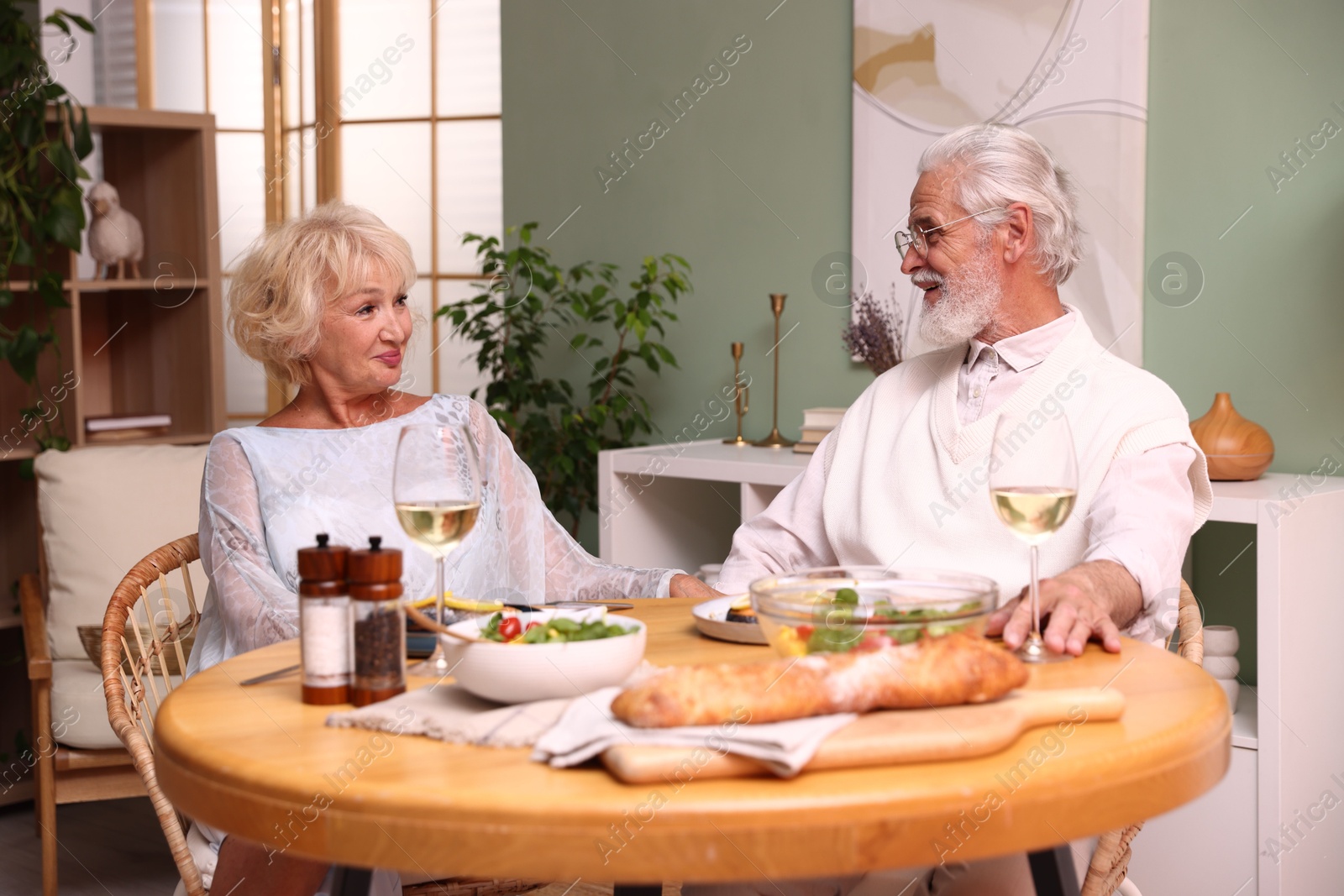 Elderly couple having dinner at table indoors Photo of Elderly couple having dinner at table indoors
