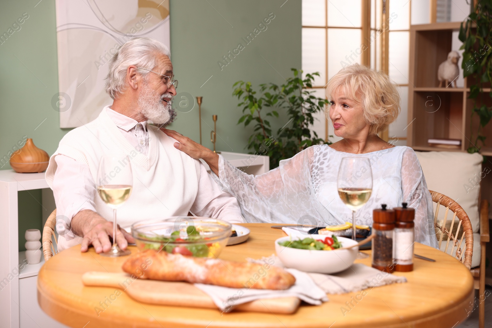 Elderly couple having dinner at table indoors Photo of Elderly couple having dinner at table indoors