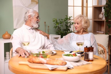 Photo of Elderly couple having dinner at table indoors