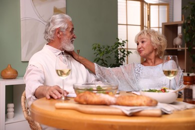 Photo of Elderly couple having dinner at table indoors