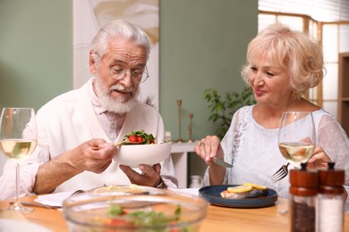 Photo of Elderly couple having dinner at table indoors