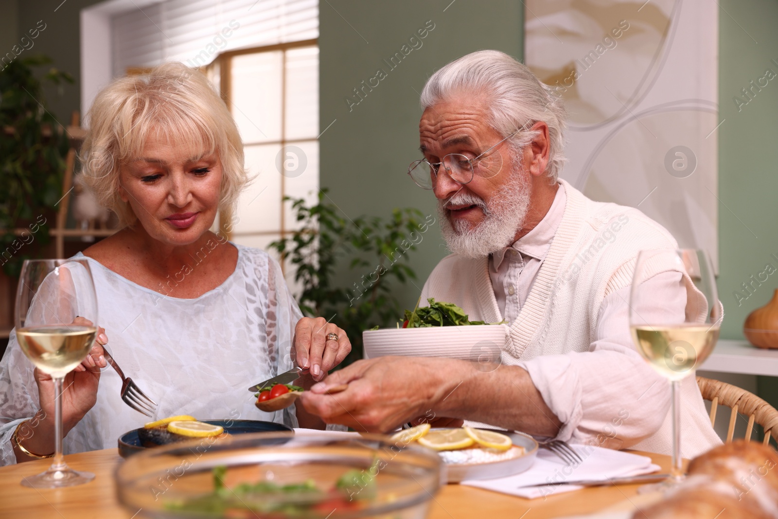 Elderly couple having dinner at table indoors Photo of Elderly couple having dinner at table indoors