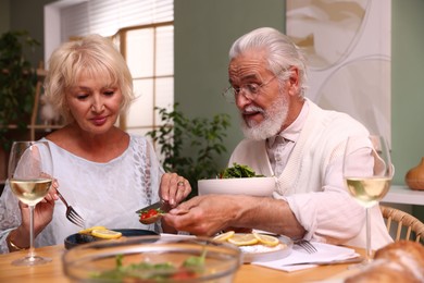 Photo of Elderly couple having dinner at table indoors