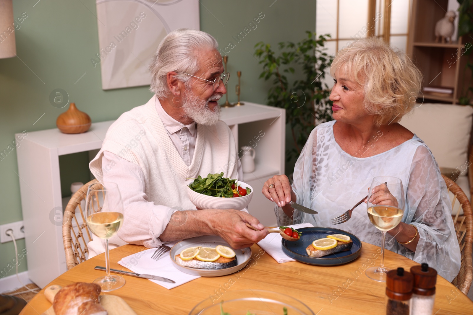 Elderly couple having dinner at table indoors Photo of Elderly couple having dinner at table indoors