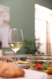 Photo of Tasty food and glass of white wine on table indoors, closeup