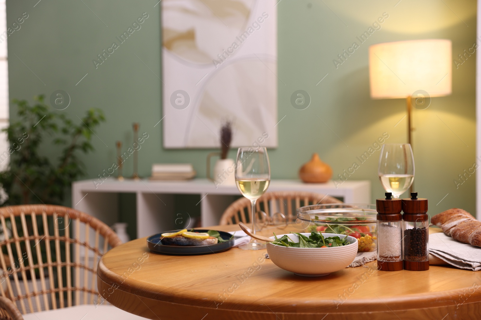 Dinner table with tasty food and white wine in stylish room Photo of Dinner table with tasty food and white wine in stylish room