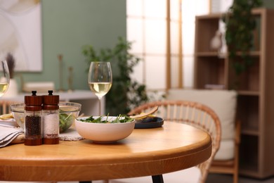 Photo of Bowl of salad, white wine and spices on table indoors