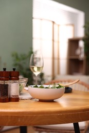 Photo of Bowl of salad, white wine and spices on table indoors