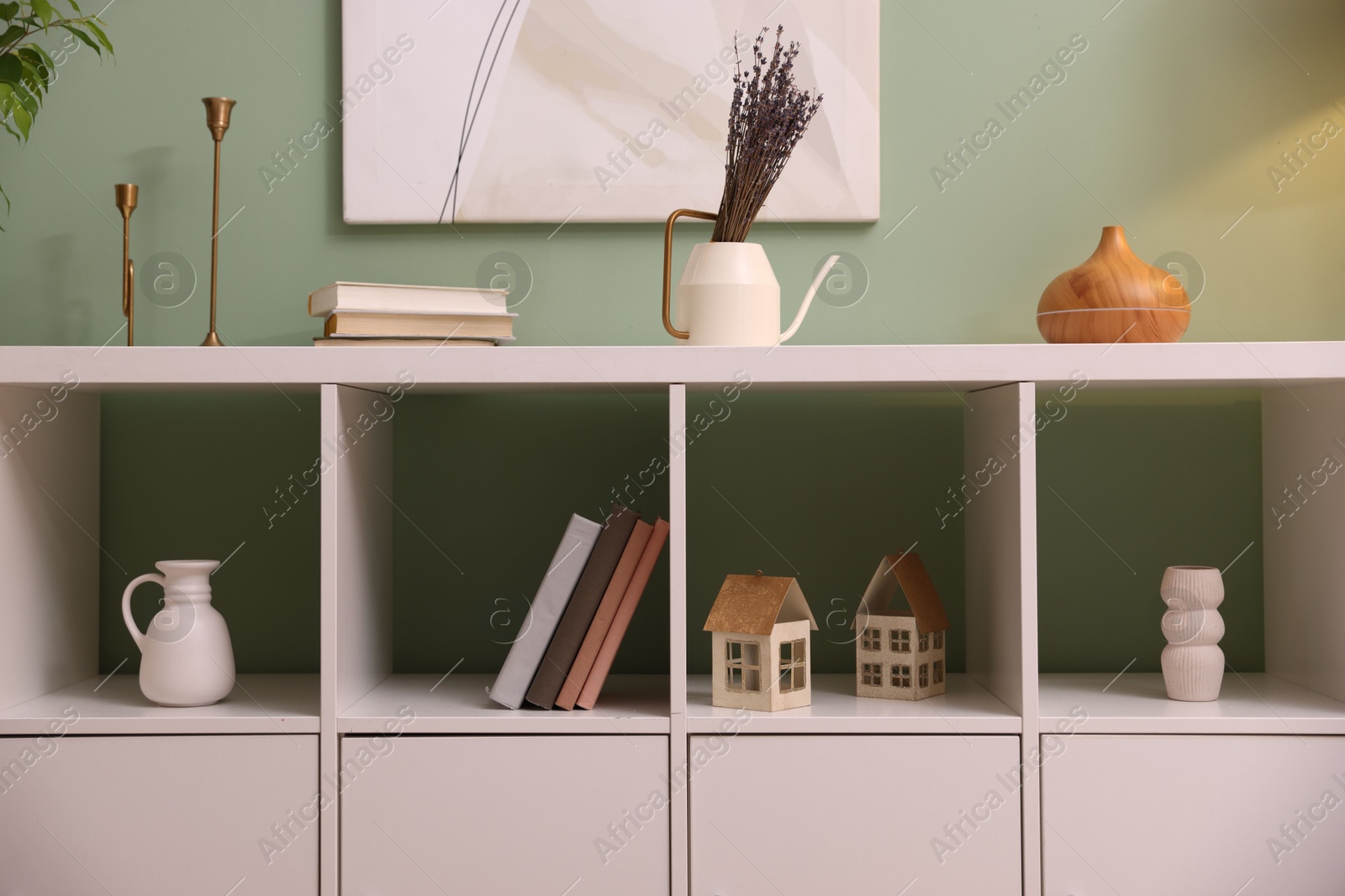 Shelving unit with decorative elements near green wall indoors Photo of Shelving unit with decorative elements near green wall indoors