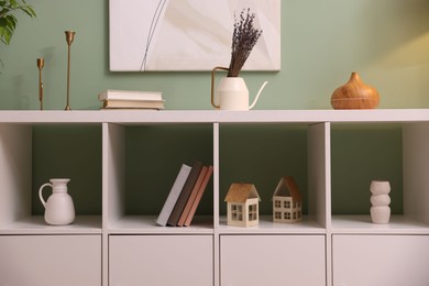 Photo of Shelving unit with decorative elements near green wall indoors
