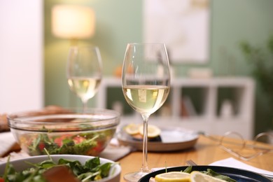 Photo of Tasty food and glasses of white wine on table indoors, closeup