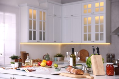 Photo of Different products and bottle of wine on counter in stylish kitchen