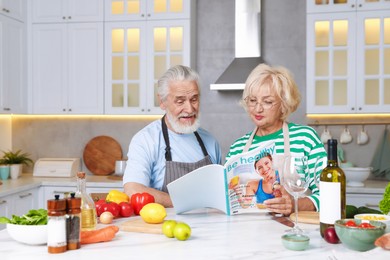Photo of Elderly couple reading magazine together at table in kitchen