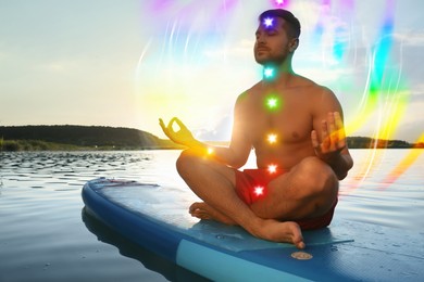 Image of Man meditating in Lotus pose on SUP board. Aura seen as rainbow waves around him. Seven chakras glowing
