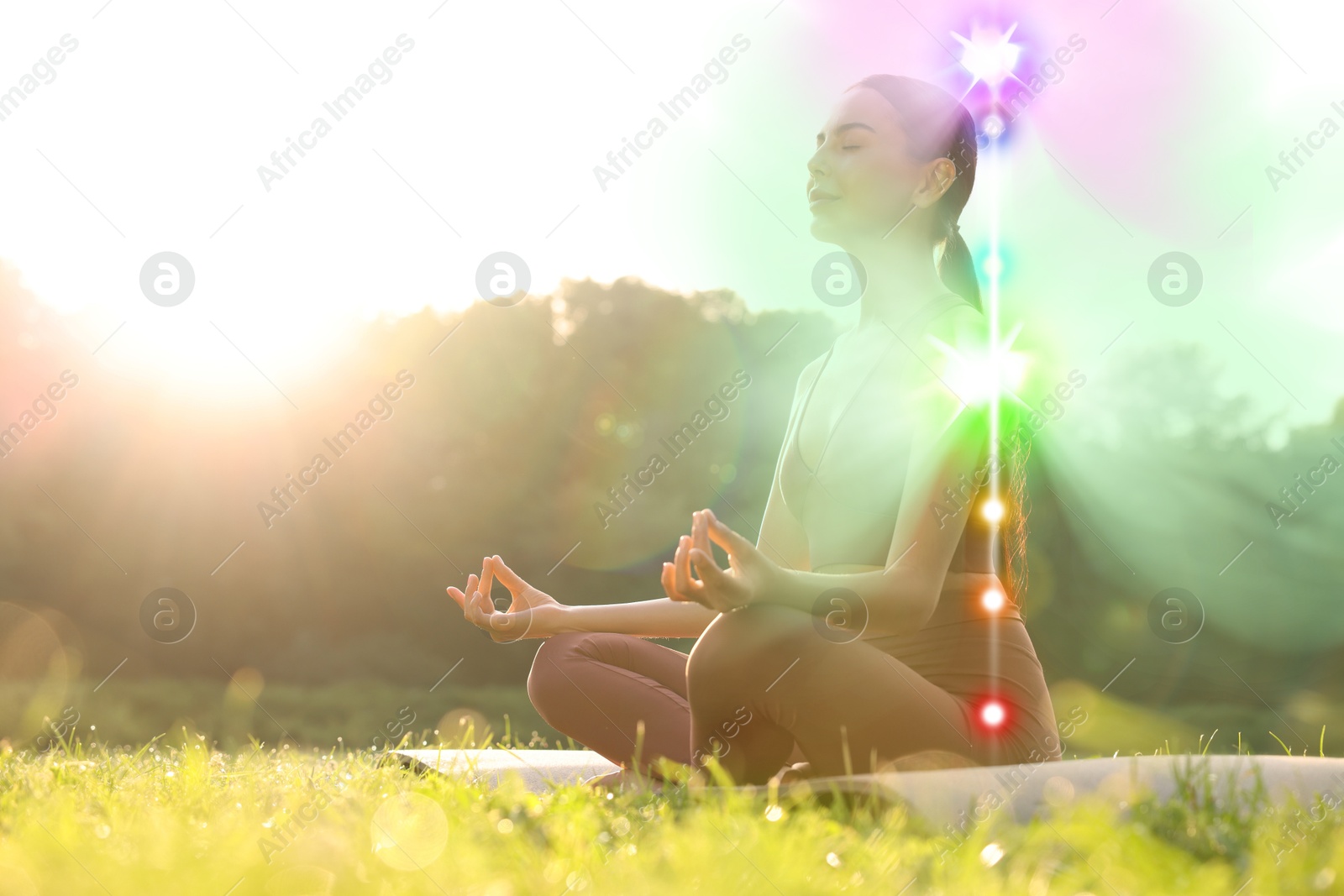 Image of Woman meditating in Lotus pose in nature on sunny morning. Seven chakras glowing