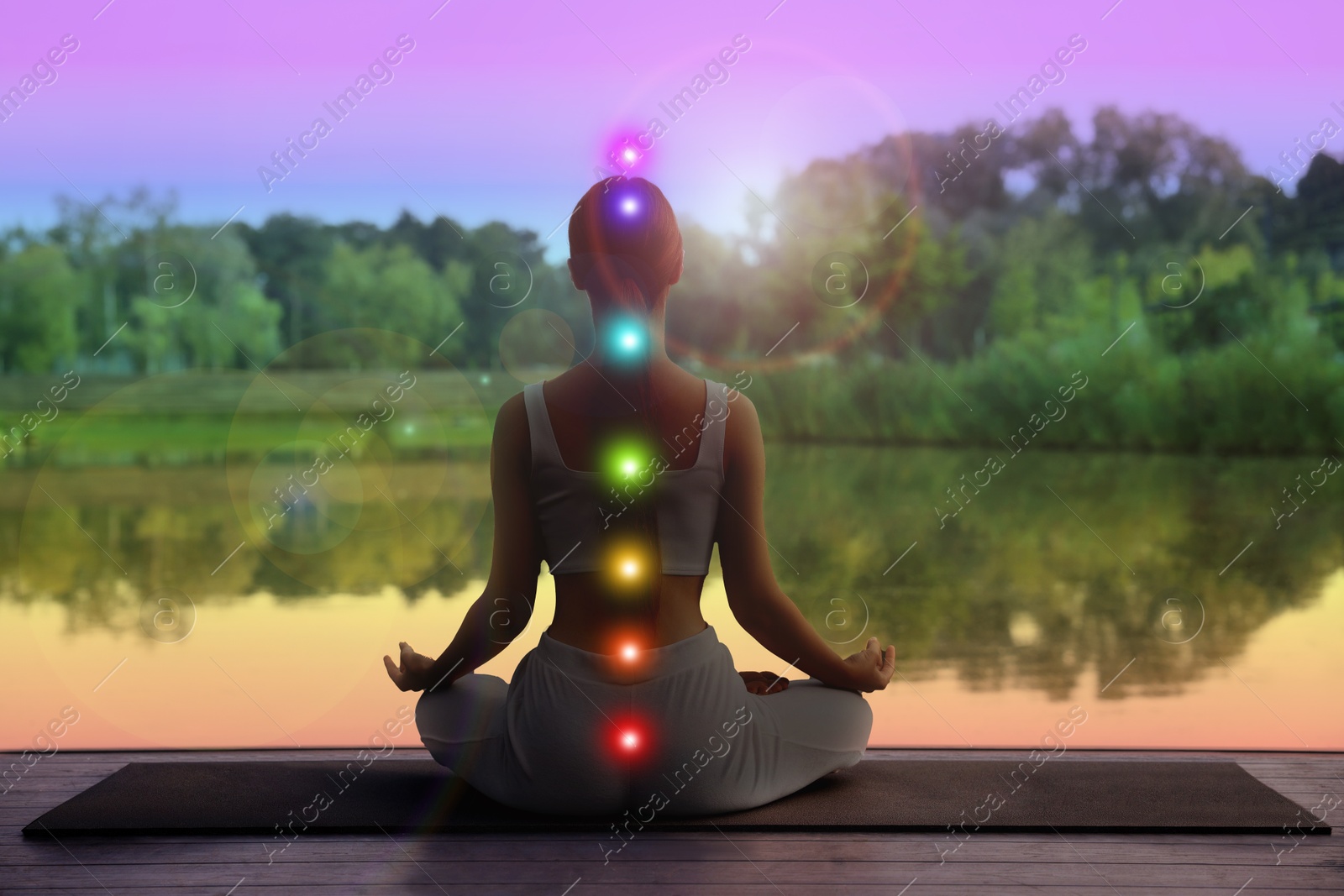 Woman meditating in Lotus pose in nature, back view. Seven chakras glowing Image of Woman meditating in Lotus pose in nature, back view. Seven chakras glowing