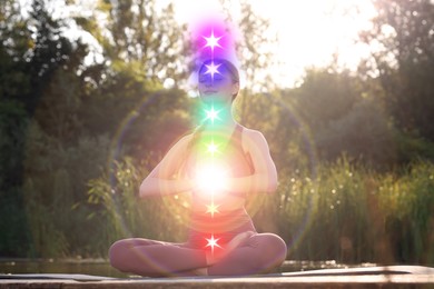 Image of Woman meditating in Lotus pose in nature. Seven chakras glowing
