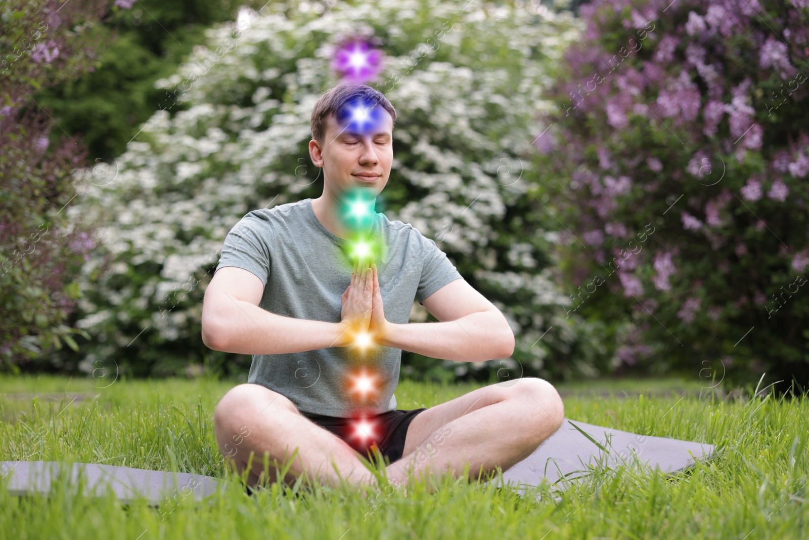 Man meditating in Lotus pose in nature. Seven chakras glowing Image of Man meditating in Lotus pose in nature. Seven chakras glowing