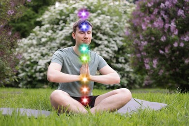 Image of Man meditating in Lotus pose in nature. Seven chakras glowing