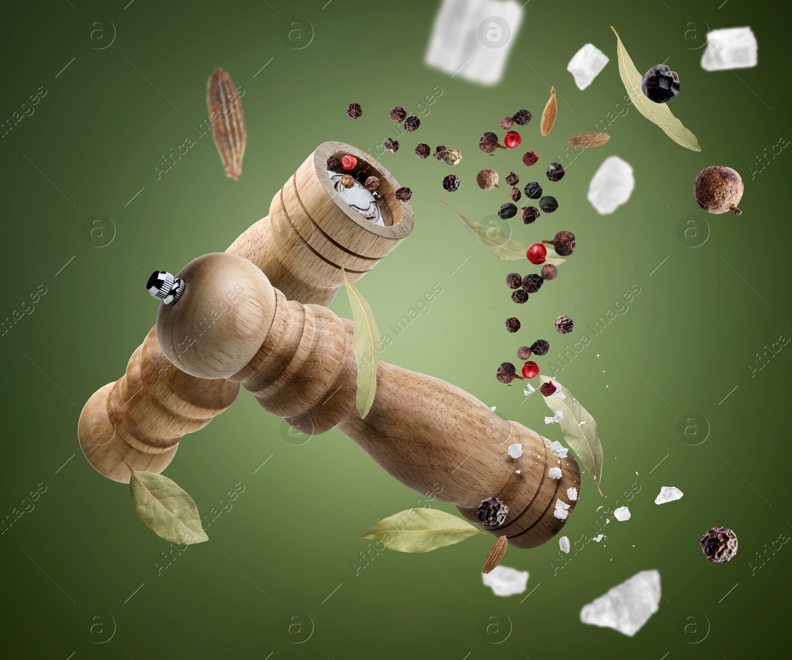 Image of Salt and pepper mills and spices flying against green gradient background