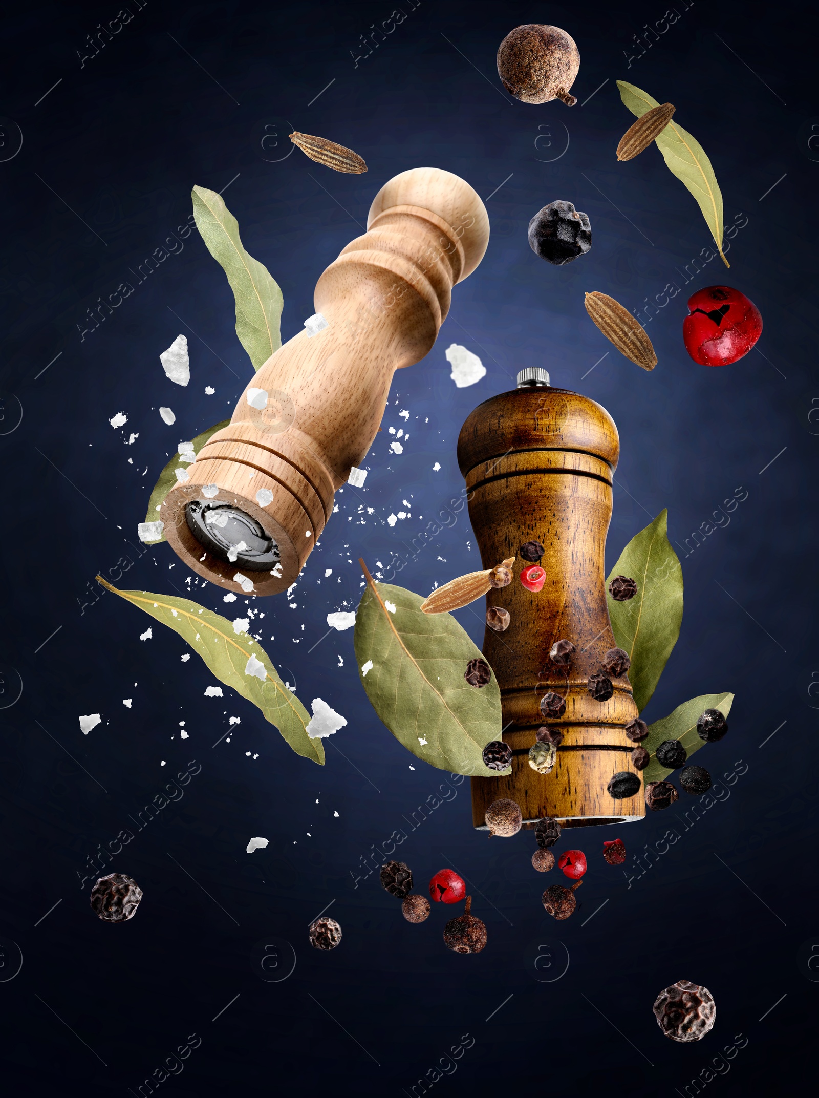 Image of Salt and pepper mills and spices flying against dark blue gradient background