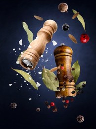 Image of Salt and pepper mills and spices flying against dark blue gradient background