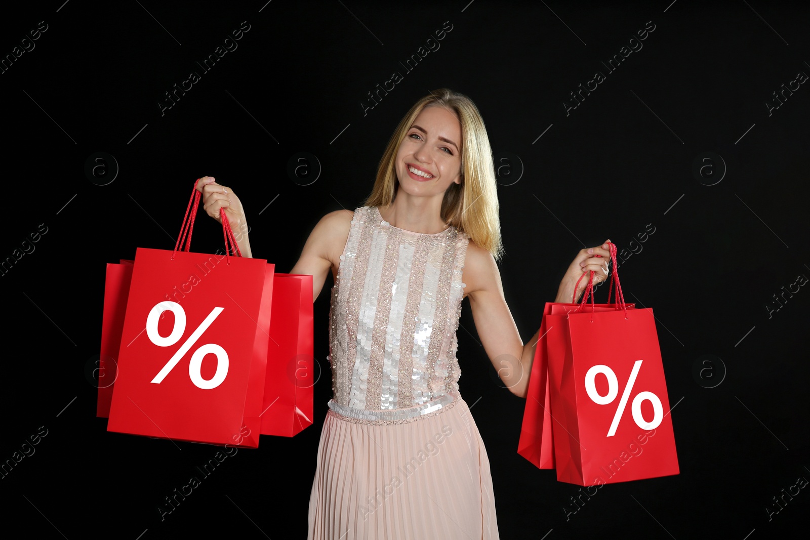 Happy woman holding shopping bags with percent signs on black background. Special offer, hot sale Image of Happy woman holding shopping bags with percent signs on black background. Special offer, hot sale