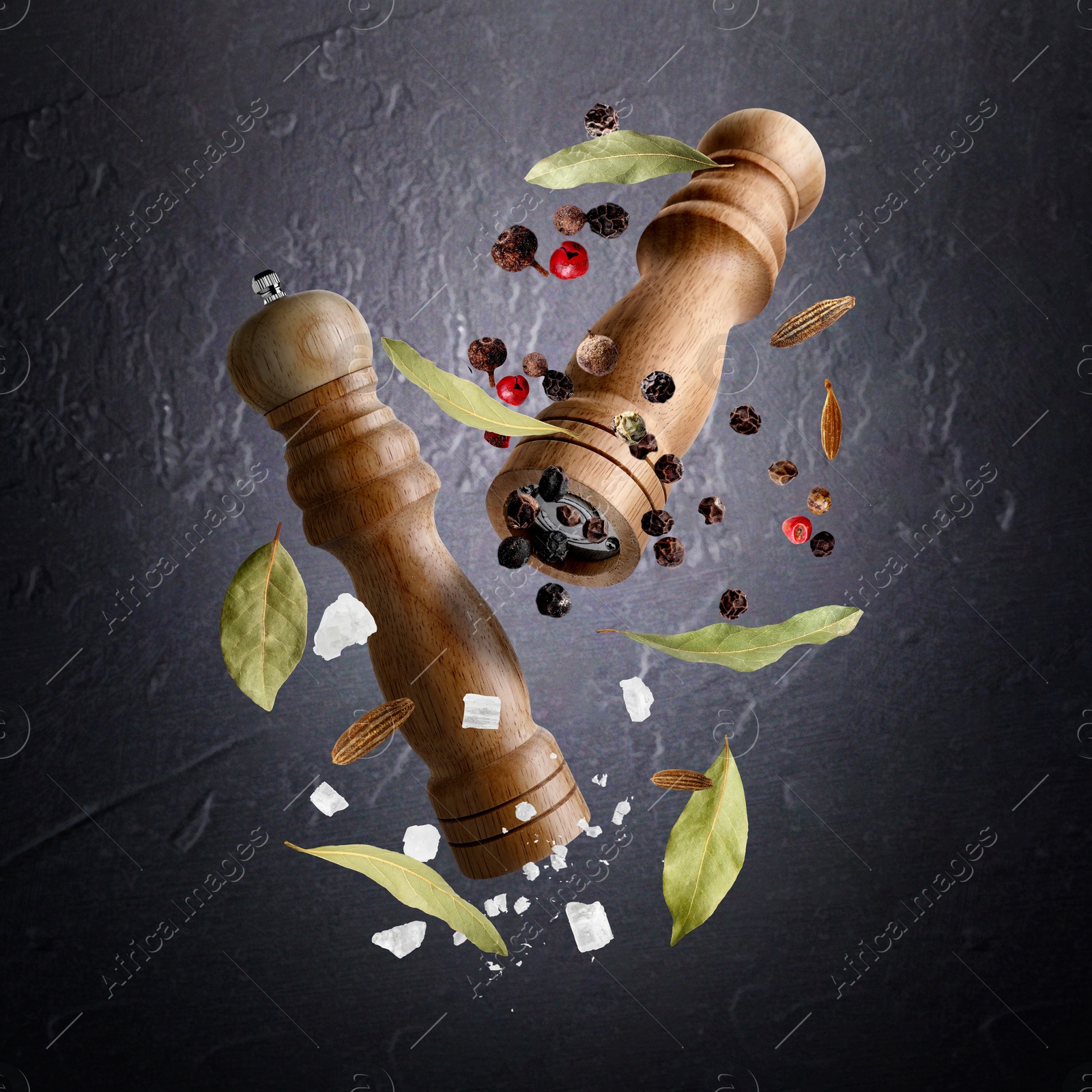 Salt and pepper mills and spices flying against dark textured background Image of Salt and pepper mills and spices flying against dark textured background