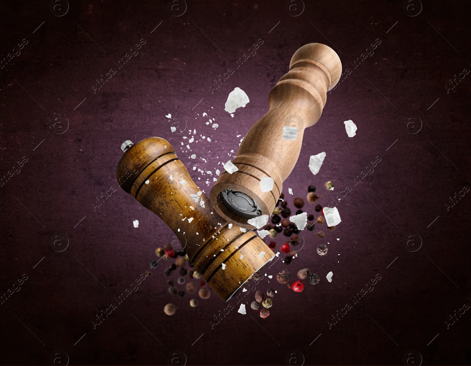 Image of Salt and pepper mills, coarse salt and peppercorns flying against dark purple background