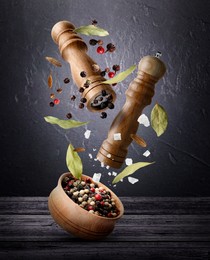 Image of Salt and pepper mills, bowl and spices in air against dark textured background