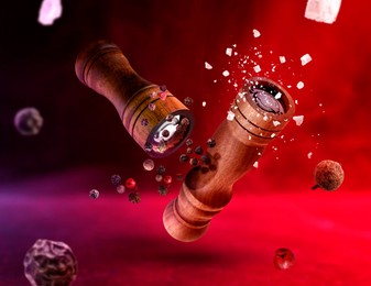 Image of Salt and pepper mills, coarse salt and peppercorns flying in red and violet lights