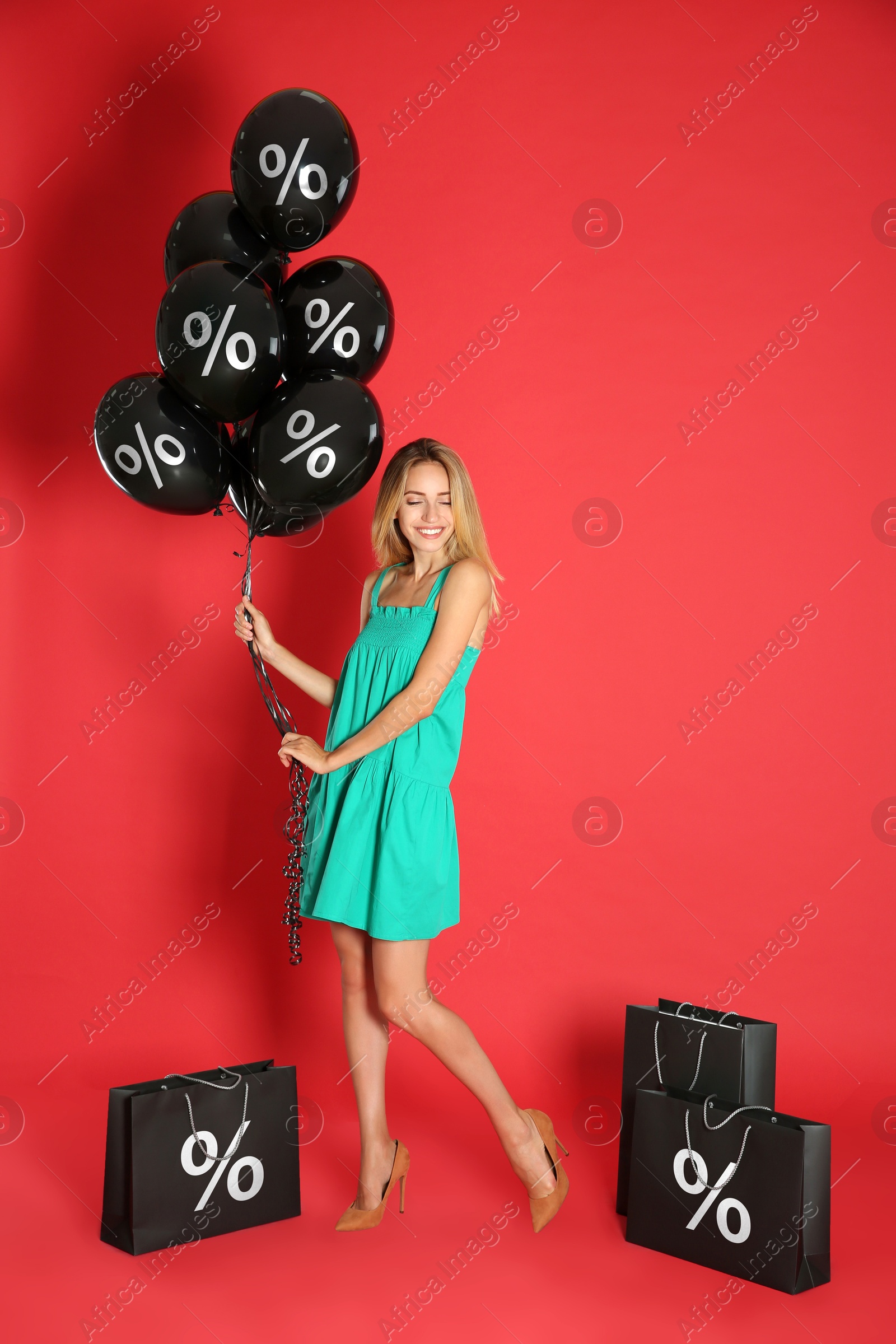 Happy woman with purchases on red background. Shopping bags and balloons with percent signs. Special offer, hot sale Image of Happy woman with purchases on red background. Shopping bags and balloons with percent signs. Special offer, hot sale