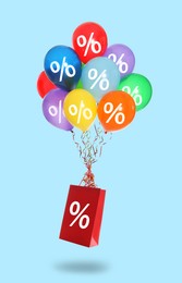Image of Hot sale, special offer. Shopping bag and balloons with percent signs in air against light blue background