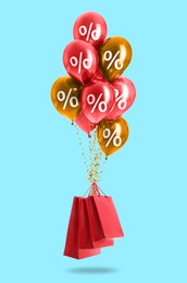 Image of Hot sale, special offer. Balloons with percent signs tied to shopping bags in air against light blue background
