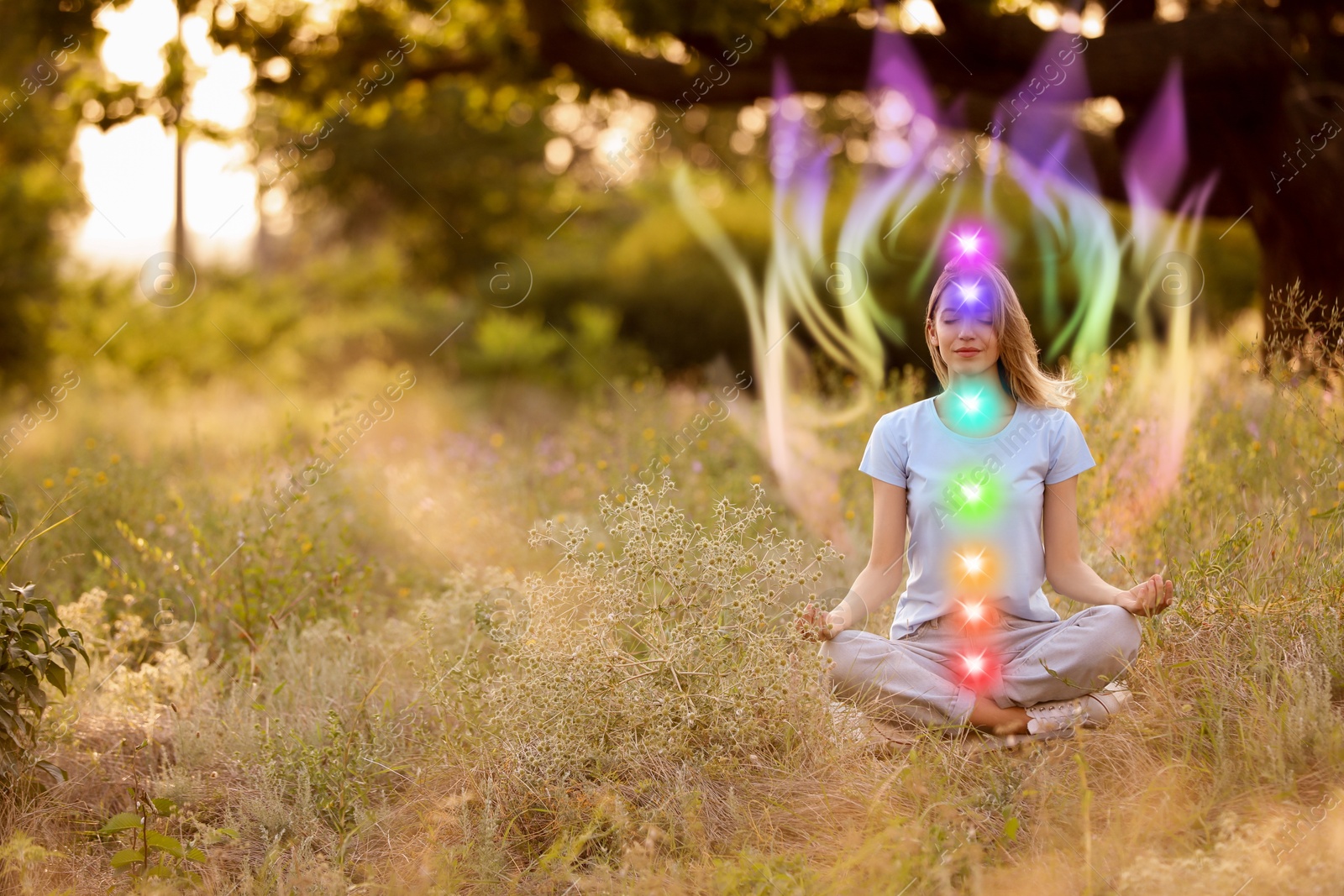 Woman meditating in Lotus pose in nature. Aura seen as rainbow waves around her. Seven chakras glowing Image of Woman meditating in Lotus pose in nature. Aura seen as rainbow waves around her. Seven chakras glowing