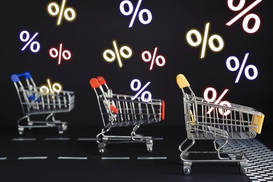 Image of Percent signs flying out of shopping carts racing on black background. Hot sale, special offer