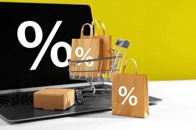 Image of Hot sale, special offer. Shopping cart, purchases and laptop against yellow background. Percent signs on device screen and shopping bags
