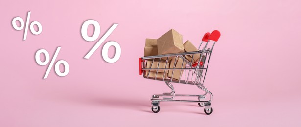 Image of Hot sale, special offer. Percent signs flying near shopping cart with boxes against pink background
