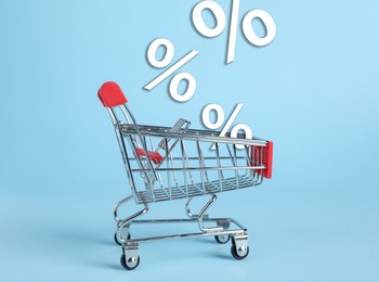 Image of Hot sale, special offer. Percent signs flying out of shopping card against light blue background