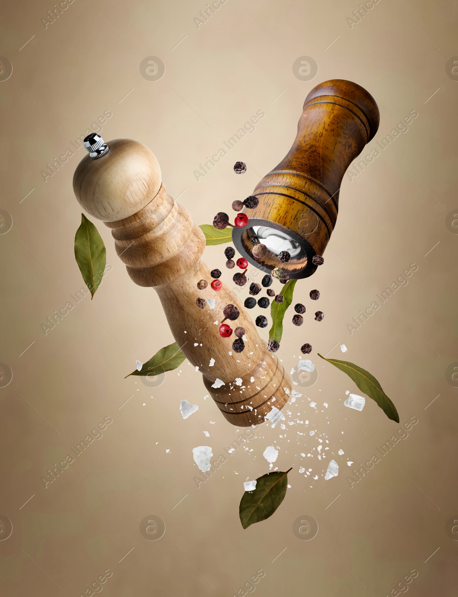 Image of Salt and pepper mills, bay leaves, coarse salt and peppercorns flying against beige gradient background