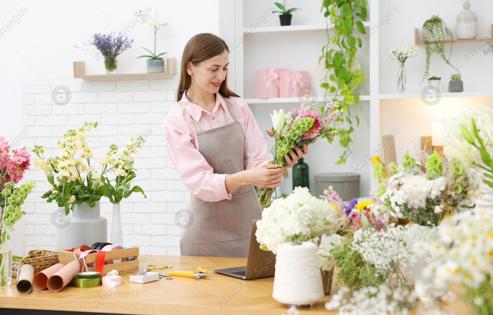 Professional florist making bouquet of flowers at wooden table in shop Photo of Professional florist making bouquet of flowers at wooden table in shop
