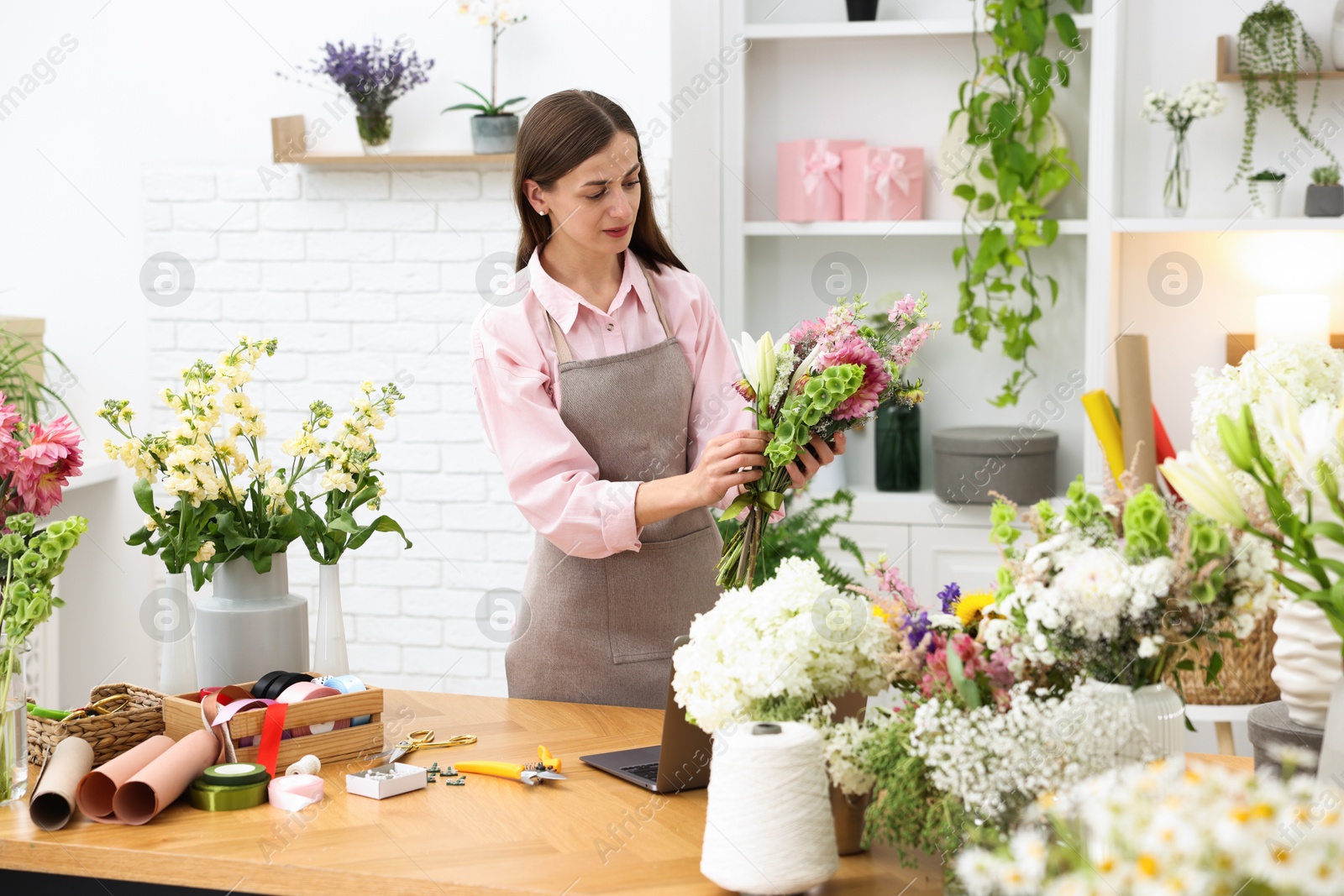 Professional florist making bouquet of flowers at wooden table in shop Photo of Professional florist making bouquet of flowers at wooden table in shop